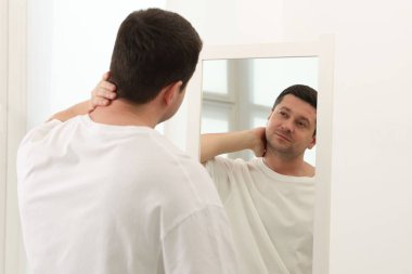 Yakışıklı adam aynada kendine bakıyor.