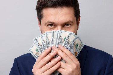 Gri arka planda dolar banknotları olan açgözlü bankacı, yakın plan.