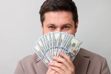 Gri arka planda dolar banknotları olan açgözlü bankacı.