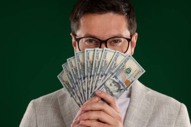 Yeşil arka planda dolar banknotları olan açgözlü bankacı, yakın plan.