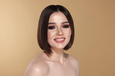 Bej arka planda harika düz saçları olan güzel, genç bir kadının portresi.