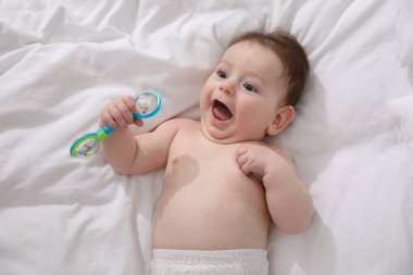 Evde yatağında çıngıraklı oyuncağı olan sevimli bir bebek.