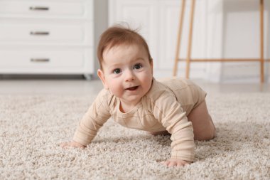 Evde yerde çıngıraklı oyuncağı olan şirin bir bebek.