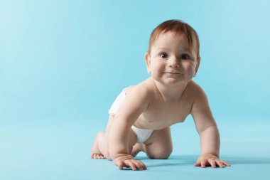 Açık mavi arka planda emekleyen şirin bir bebek. Metin için boşluk