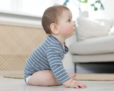 Evde yerde oturan şirin bir bebek.