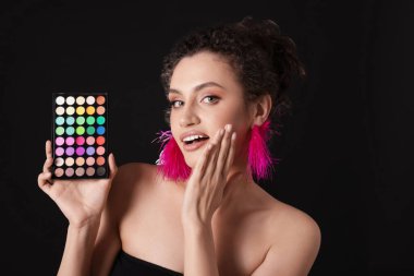 Siyah arka planda parlak göz falı olan şaşırmış bir kadın.