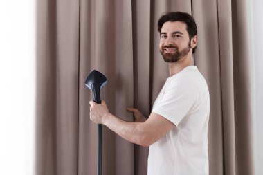 Evde buharlı perdeleri olan bir adam.