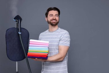 Buharlı vapurlu ve gri arka planda bir yığın elbisesi olan bir adam.