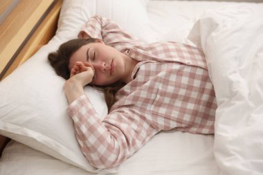 Evde yatakta uyuyan genç kadın.