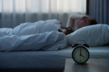 Evde yatakta uykusuzluk çeken sinirli genç kadın, alarma odaklan.