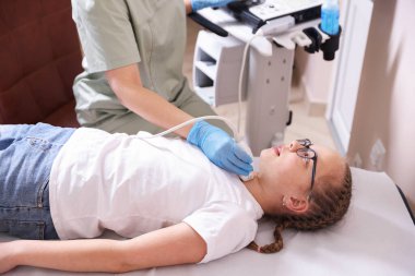 Sonograf, klinikte kızın tiroid bezi ultrason muayenesini yönetiyor.