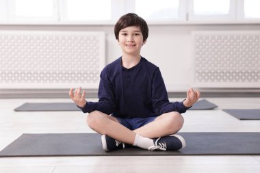 Kapalı alanda yoga yapan mutlu çocuk.