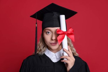 Mezuniyetten sonra kırmızı arka planda diploması olan güzel bir öğrenci.
