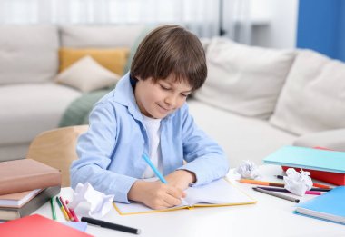Evde, masada ödev yapan sevimli küçük çocuk.