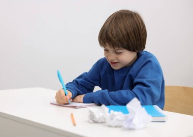 İçeride masa başında ödev yapan sevimli küçük çocuk.