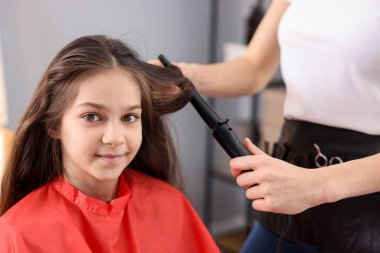 Güzel kız kuaförde saç buklesi yaptırıyor.