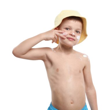 Küçük çocuk beyaz arka planda cildine güneş kremi sürüyor.