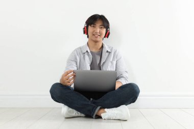 Kulaklık ve dizüstü bilgisayarı olan öğrenci içeride ders çalışıyor.