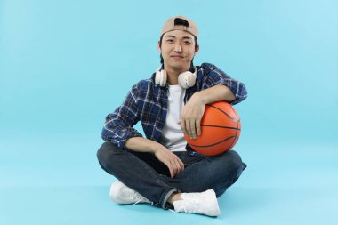 Kulaklıklı öğrenci ve açık mavi arka planda basketbol topu.
