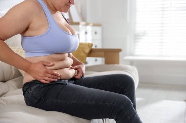 Evde göbeği aşırı yağlı bir kadın, yakın çekim ve mesaj için yer. Aşırı kilolu