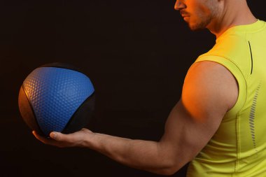 Siyah arka planda tıp topu olan adam, yakın plan.