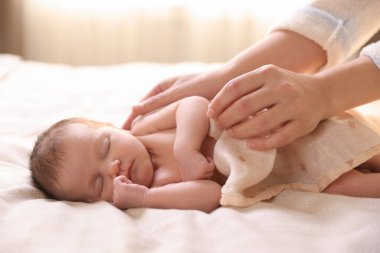 Yatma vakti. Anne uyuyan bebeğini battaniyeyle örtüyor.