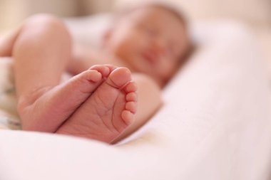 Küçük bebek evde yatakta uzanıyor, seçici bir odak noktası. Metin için boşluk