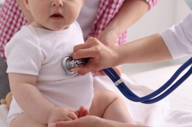 Klinikte steteskopla bebeği muayene eden çocuk doktoru.