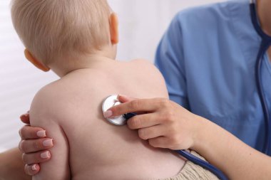 Klinikte steteskopla bebeği muayene eden çocuk doktoru.