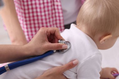 Klinikte steteskopla bebeği muayene eden çocuk doktoru.