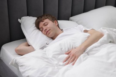 Genç adam yatağında uyuyor.
