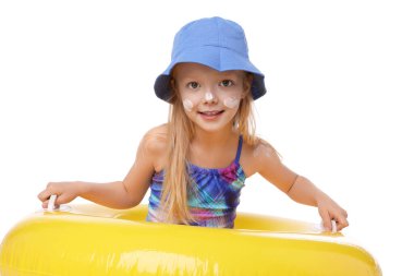 Cildinde güneş kremi ve beyaz arka planda şişme yüzük olan gülümseyen küçük bir kız.