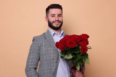 Bej arka planda kırmızı gül buketi olan mutlu adam.