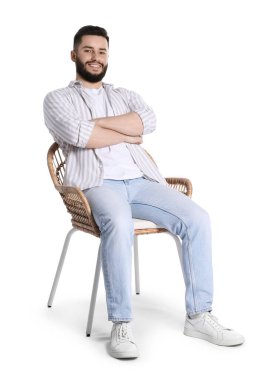 Gülen adam beyaz arka planda sandalyede dinleniyor.