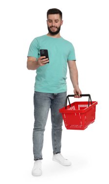 Beyaz arka planda akıllı telefon kullanan boş alışveriş sepetli bir adam.