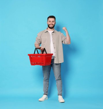 Açık mavi arka planda boş alışveriş sepeti olan bir adam.