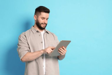 Açık mavi arkaplanda tablet kullanan adam, metin için boşluk