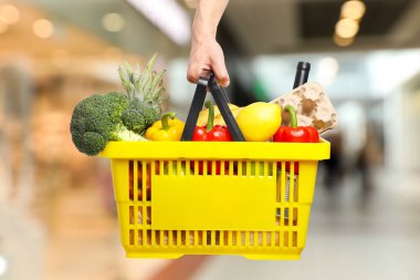 Süpermarkette elinde farklı gıda ürünleri olan bir adam var.