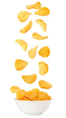 Lezzetli patates cipsleri beyaz arka planda kaseye düşüyor.