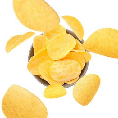 Lezzetli patates cipsleri beyaz arka planda kaseye düşüyor.