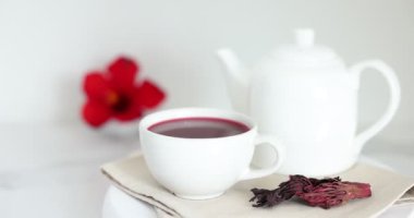 Fincanda leziz amber çayı, çaydanlık ve kuru roselle sepals beyaz masada, yakın plan.