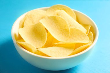 Açık mavi ahşap masada patates cipsi, yakın plan.