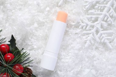 Nemlendirici dudak kremi ve yapay karla süslenmiş Noel süsü. Kış bakımı