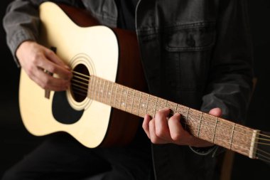 Siyah arkaplanda gitar çalan adam, yakın plan