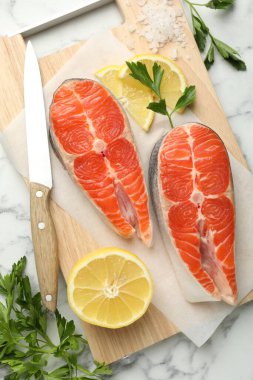 Deniz ürünleri. Taze çiğ somon bifteği, maydanoz, beyaz mermer masada limon ve tuz parçaları, düz uzanmış.