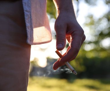 Parkta sigara içen adam, yakın çekim manzaralı.