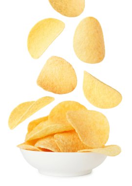 Lezzetli patates cipsleri beyaz arka planda kaseye düşüyor.