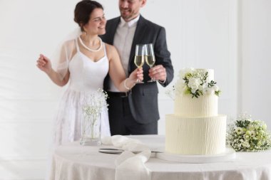 Mutlu evli çift içeride, düğün pastasına ve masadaki bukete odaklan.