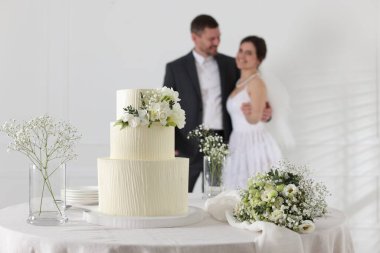 Mutlu evli çift içeride, düğün pastasına ve masadaki bukete odaklan.