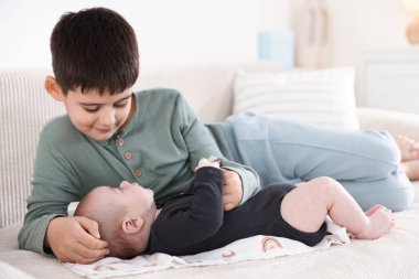 Evdeki kanepede oturan sevimli küçük kardeşler.